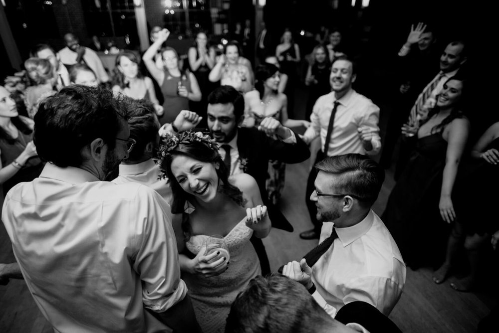the bride having a laugh as she is surrounded by the groomsmen during a dance