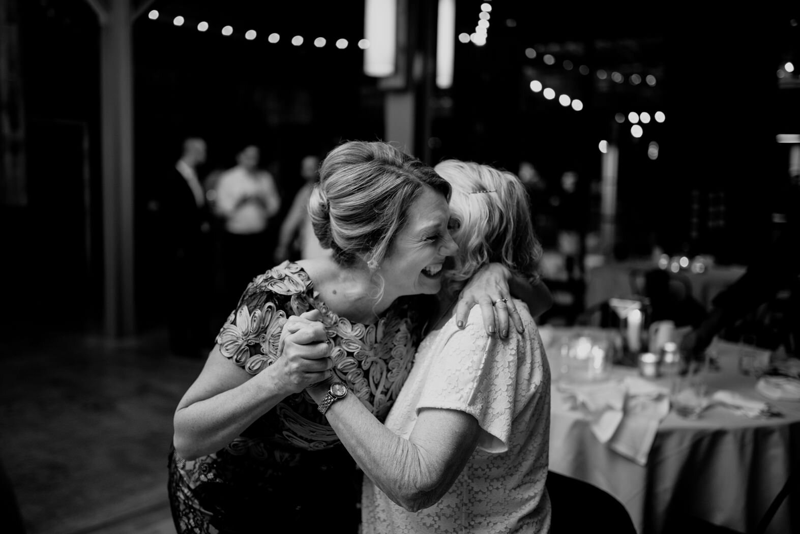 the mother of the bride hugging her mother-in-law and laughing during the reception