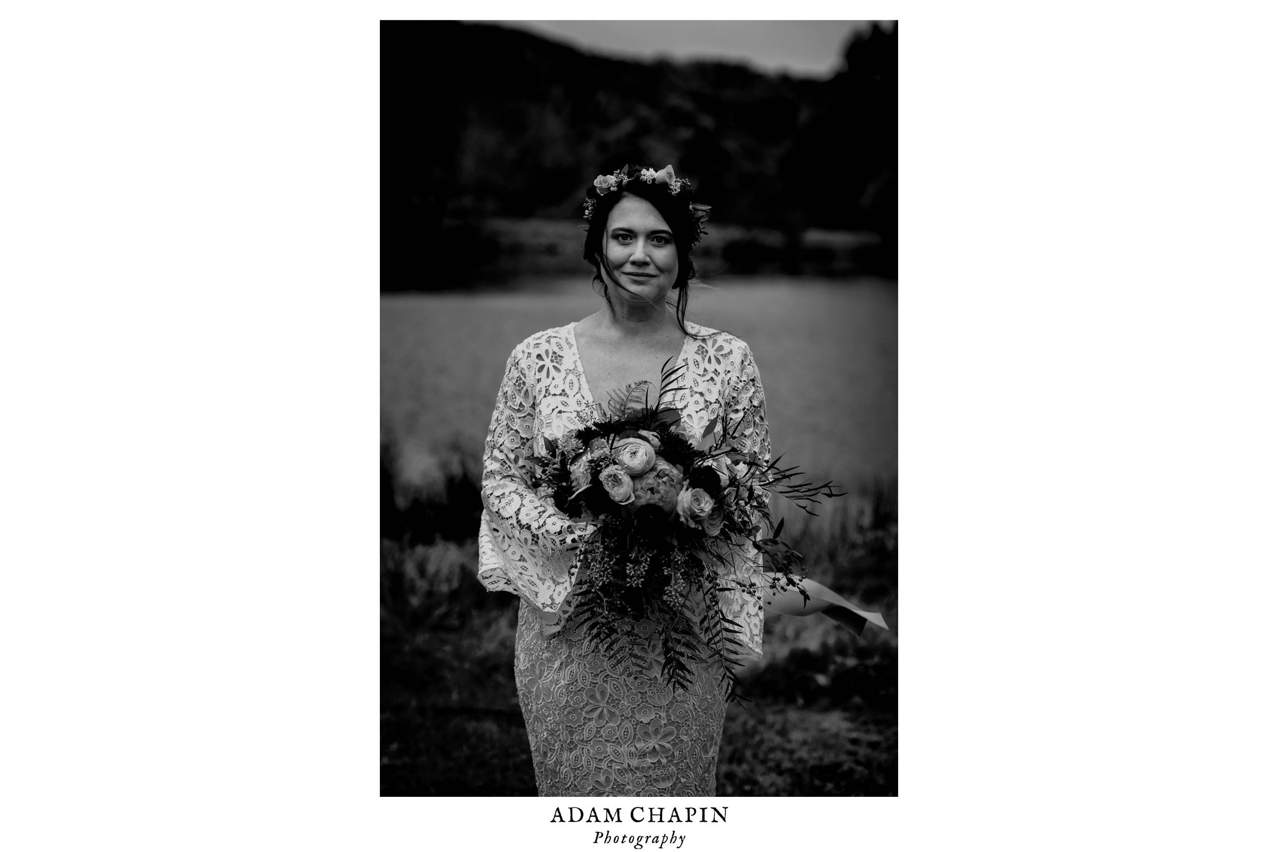 black and white photograph of bride holding her bouquet as the wind sweeps her hair across her face