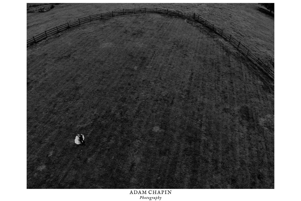 black and white drone photograph of bride and groom in the field in front of claxton farm