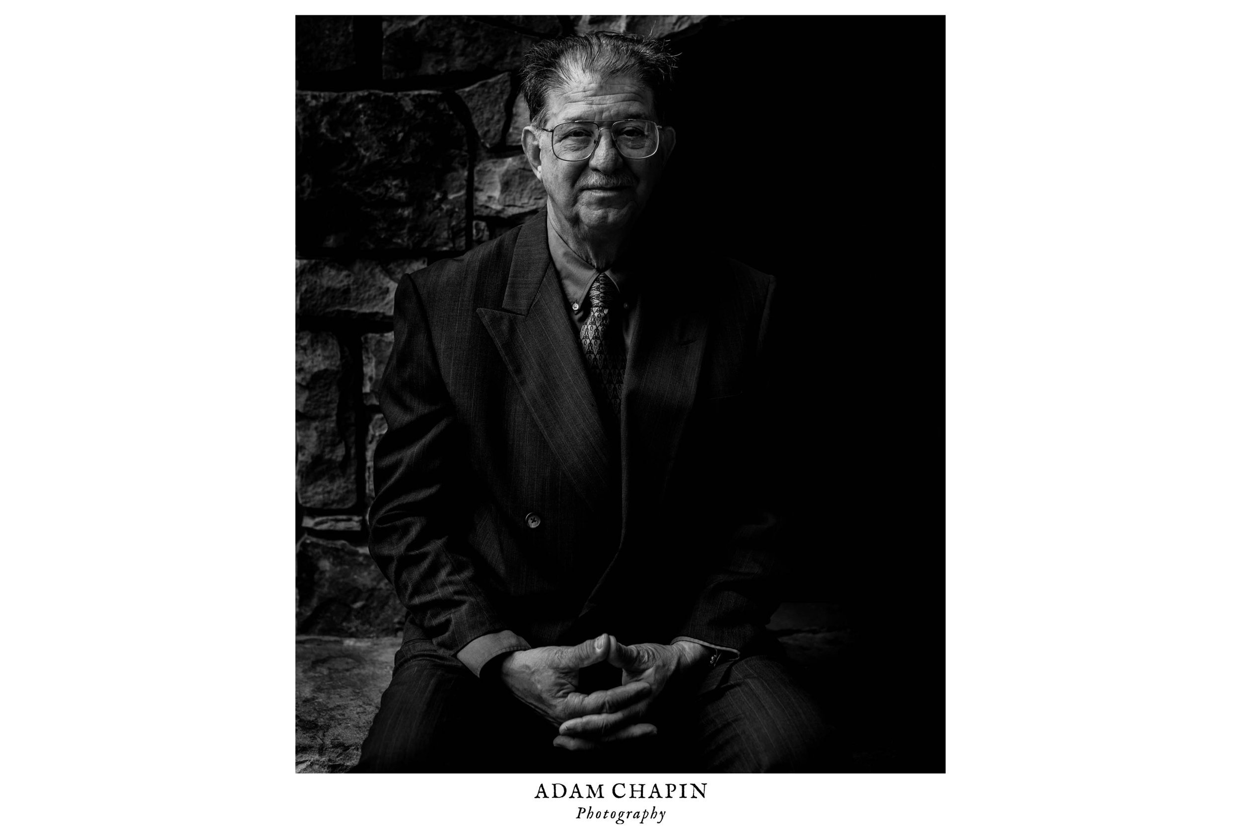 black and white portrait of the brides uncle sitting on the fireplace