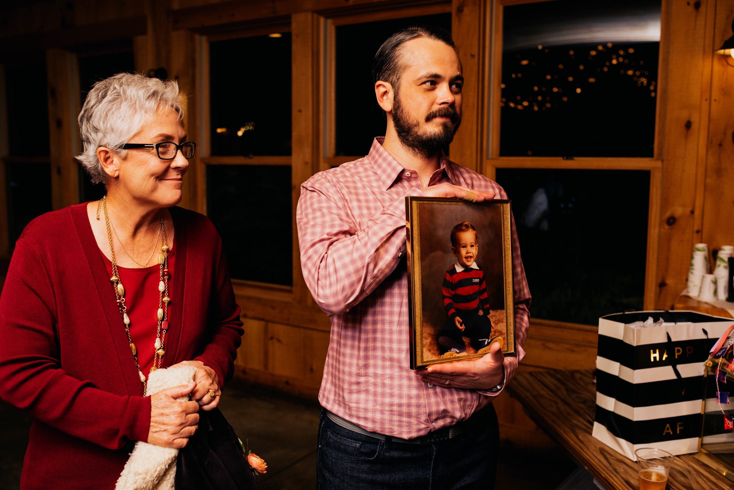 groom holding up a wedding gift of a portrait of himself as a kid