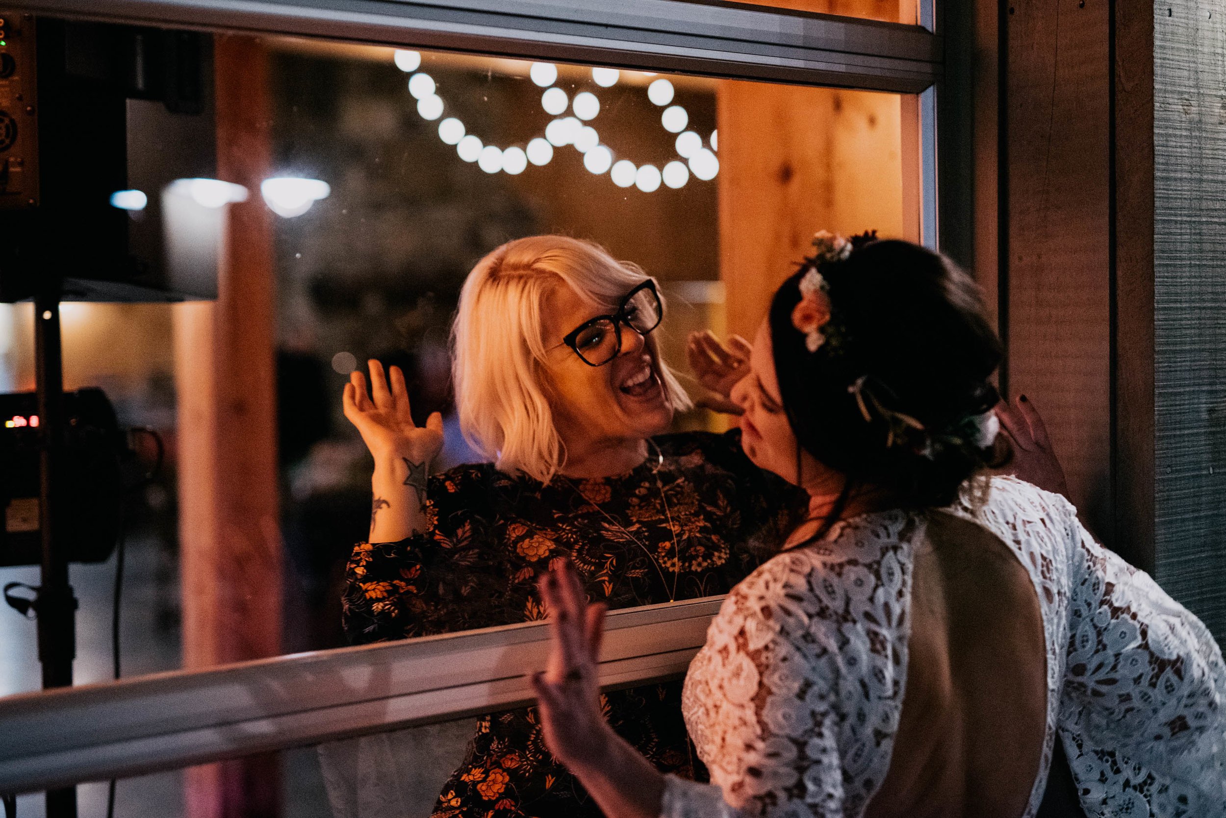 bride and her friend dancing on either side of the window