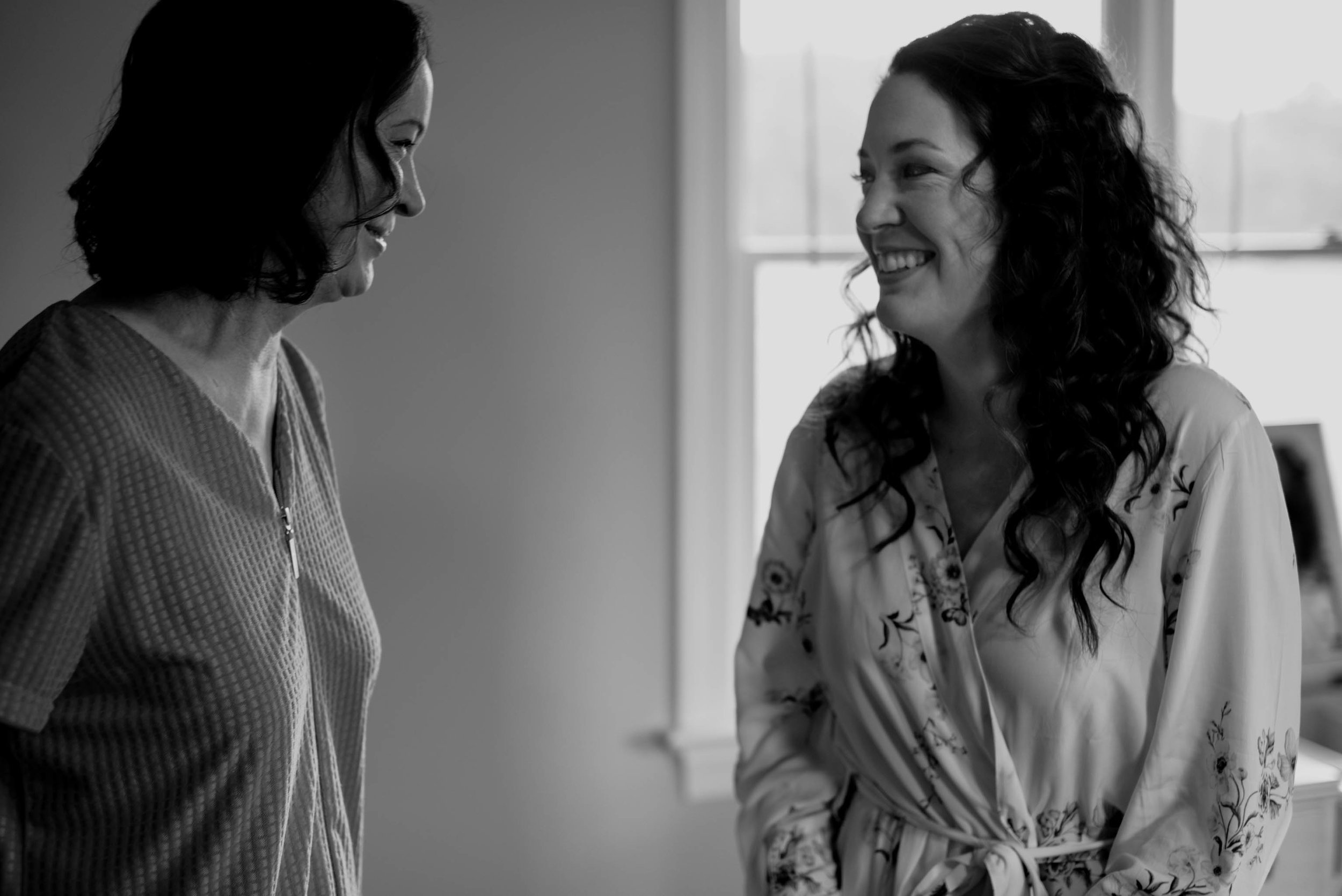 bride and her mom sharing a laugh after the brides hair and makeup were finished