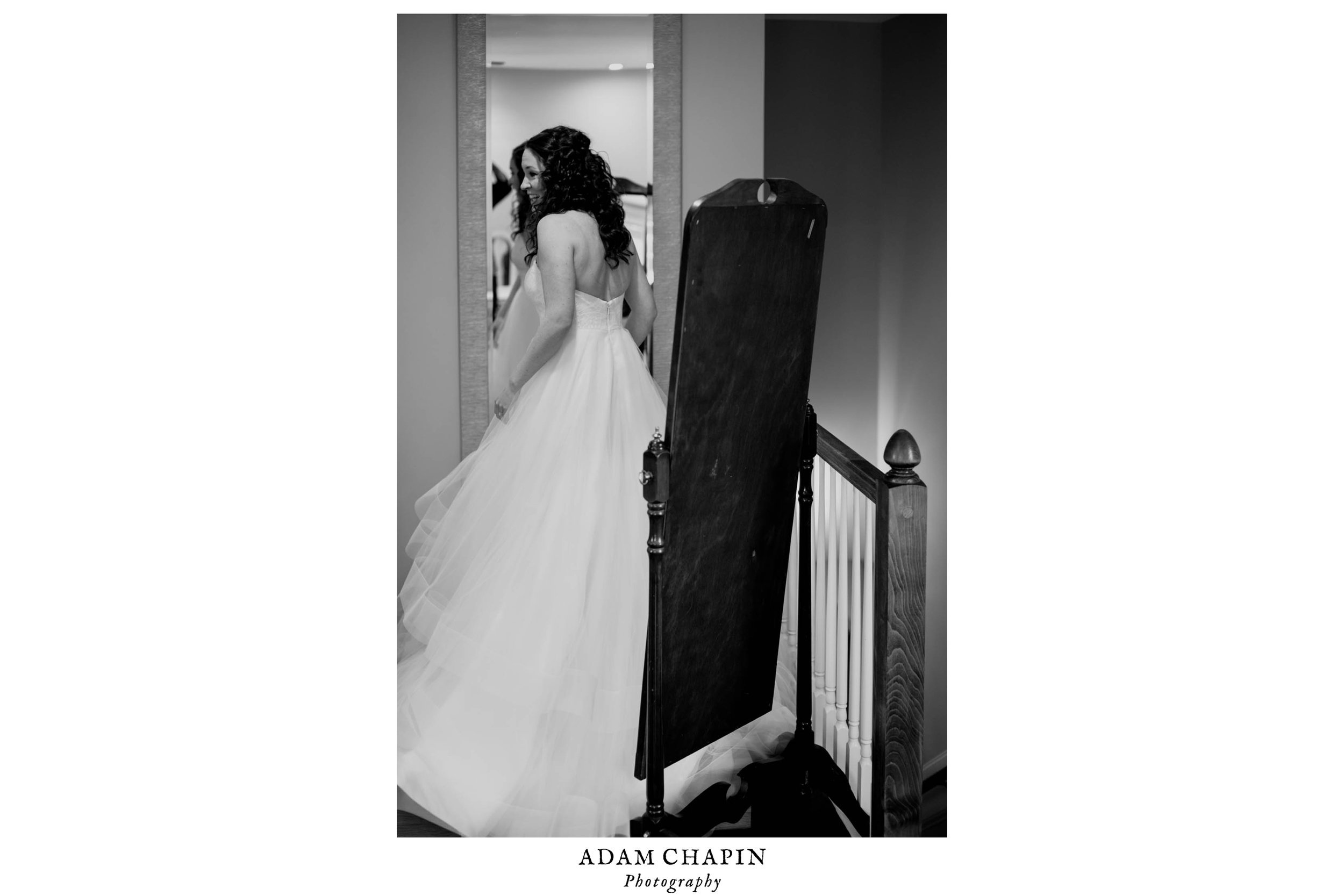 black and white photo of the bride doing on final look in the mirror before heading downstairs