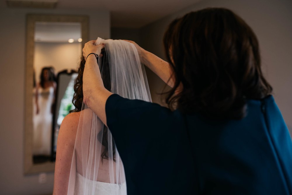 mother of the bride fixes the brides veil in place