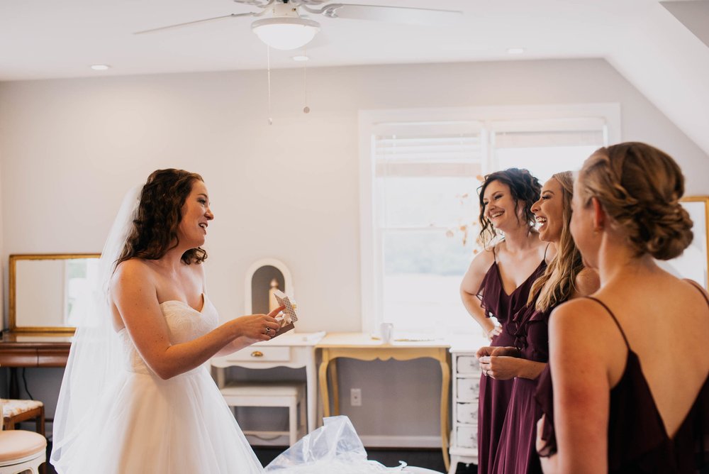 bride opening a wedding gift to her from her bridesmaids