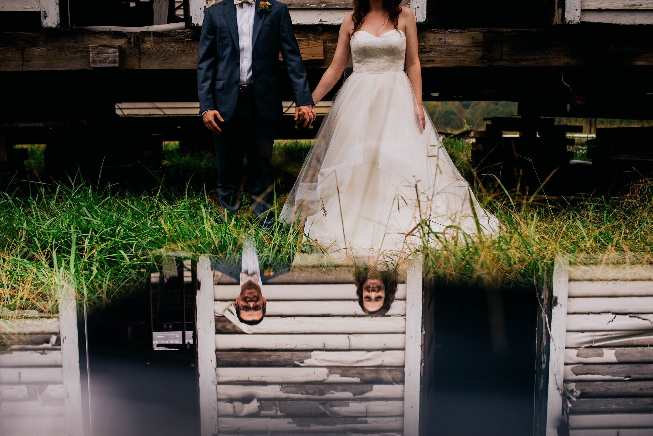 bride and groom as seen through a reflection on a piece of glass