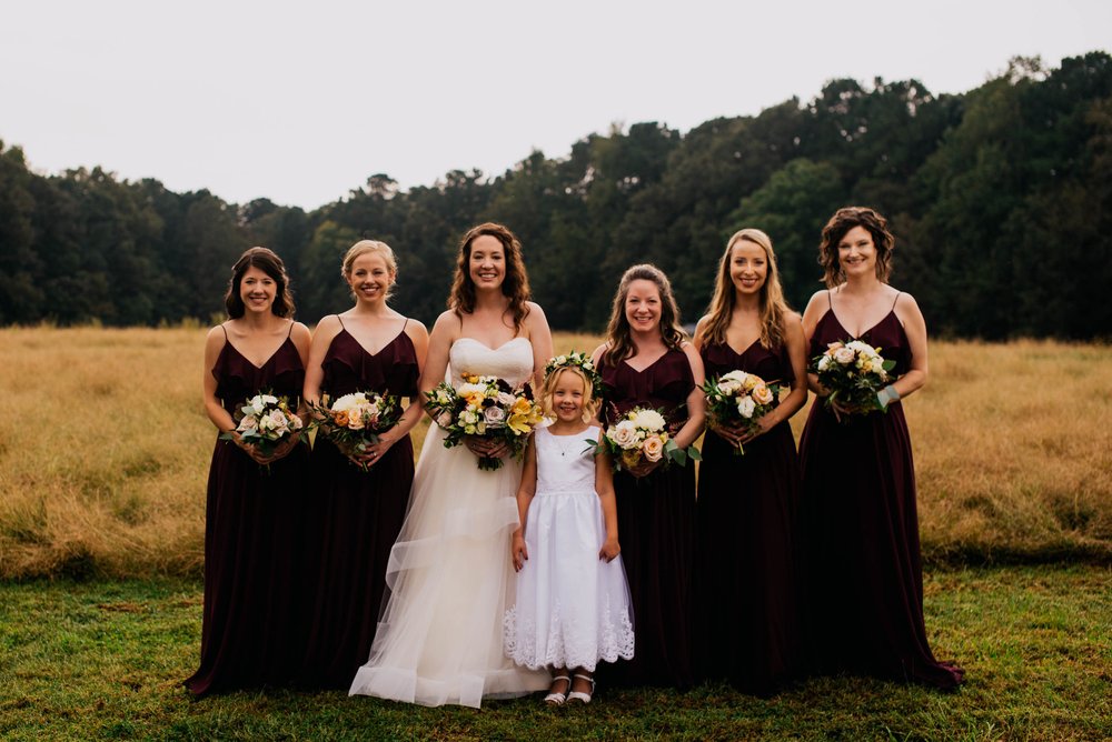bride and her bridesmaids with the flower girl posing for a photo before the wedding ceremony