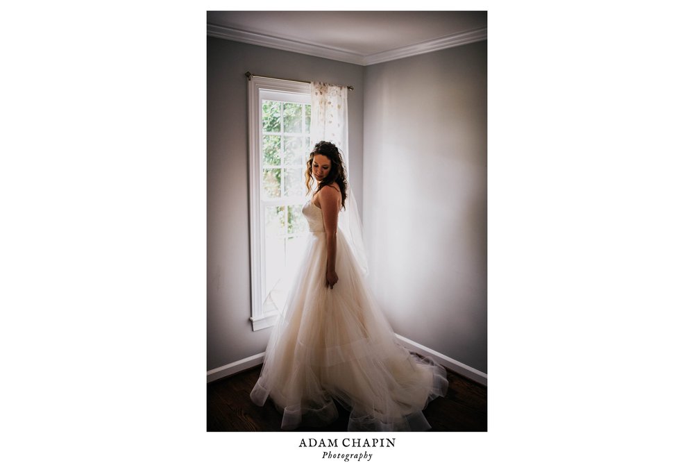 bride posing by a window in her wedding dress before her wedding ceremony
