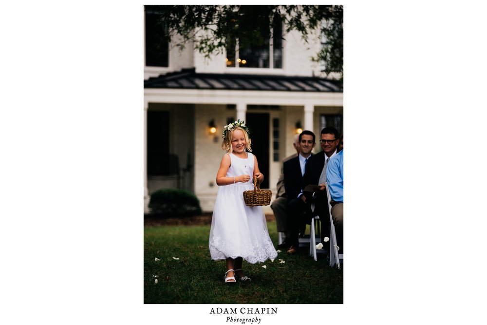 flower girl smiling and tossing flowers at the start of the wedding ceremony