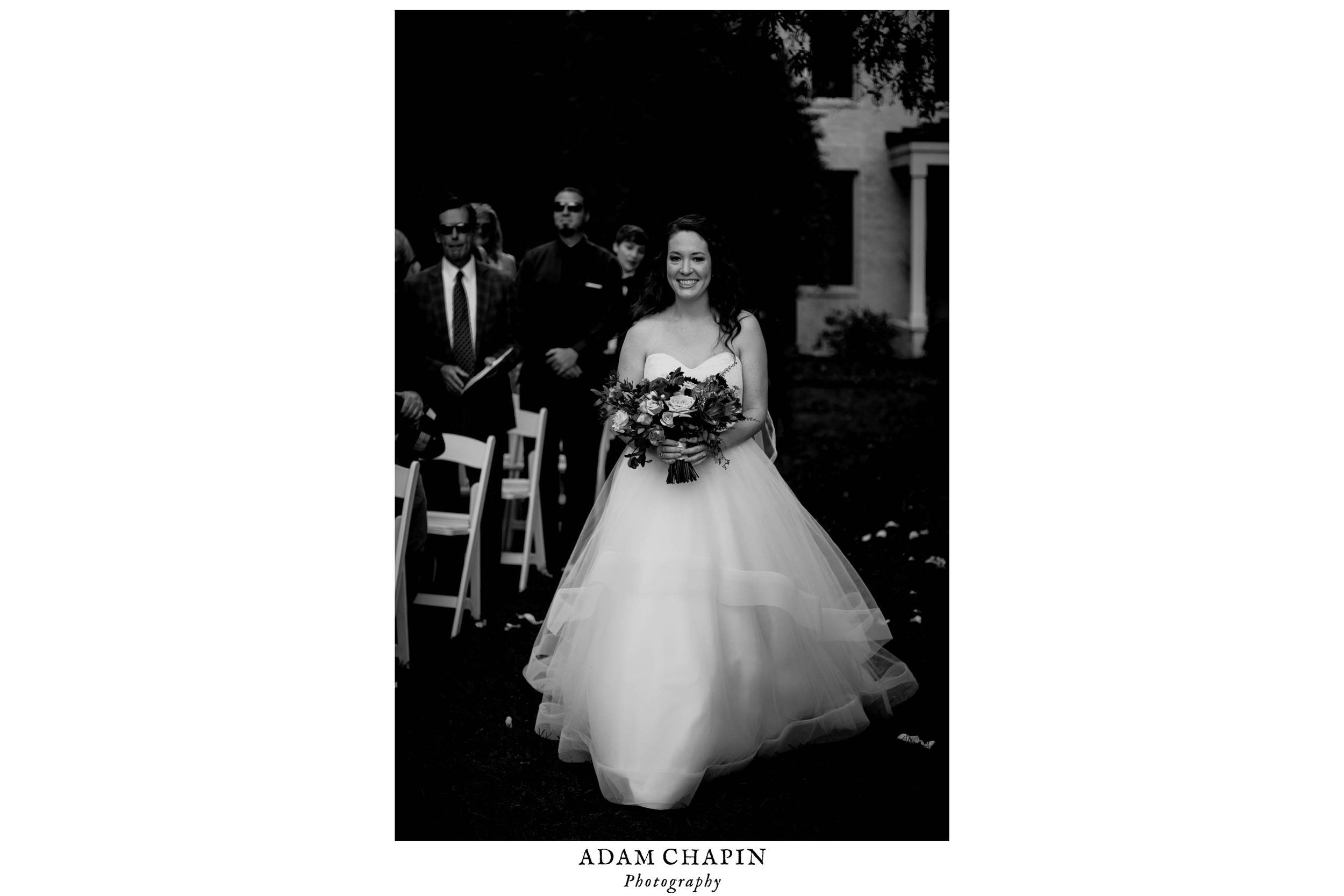 black and white photo of the bride walking down the aisle at the start of the wedding ceremony