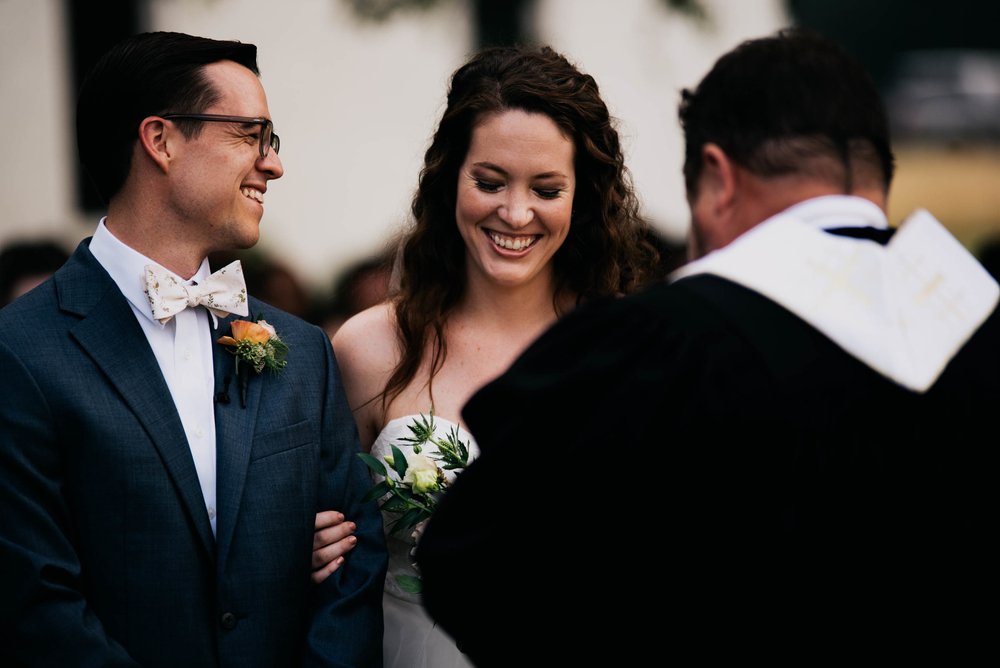bride and groom laughing at a joke that the officiant shared during their wedding ceremony