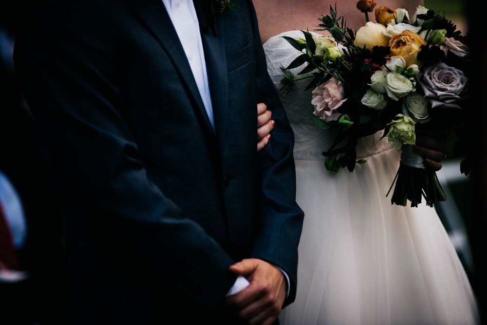 a cropped photo of the bride holding on to the groom during their wedding ceremony