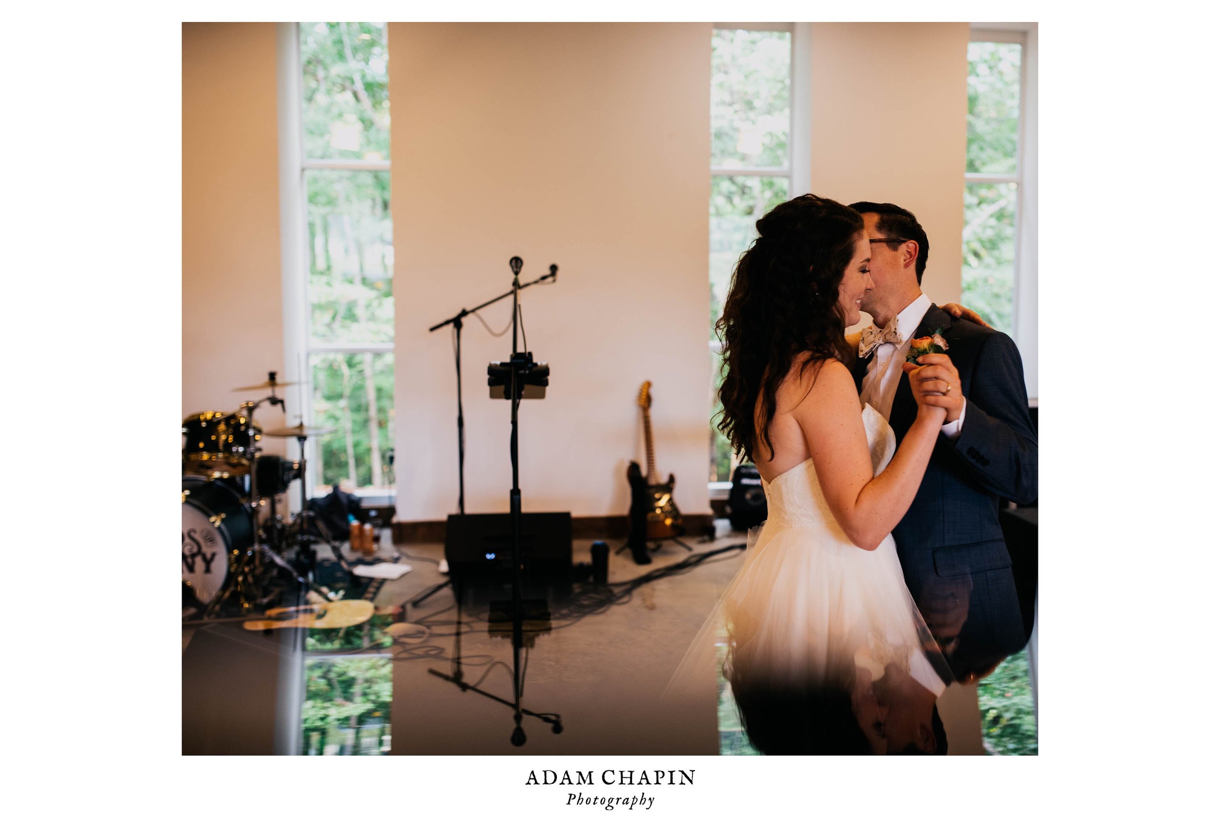 bride and groom enjoying their first dance and a kiss as seen on the reflection from a piece of glass