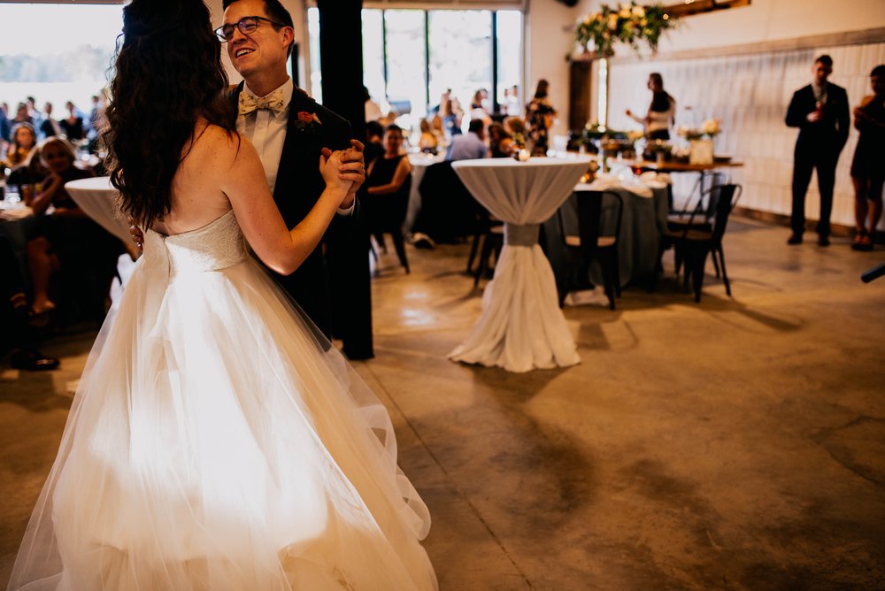 bride and groom enjoying their first dance as wedding guests look on