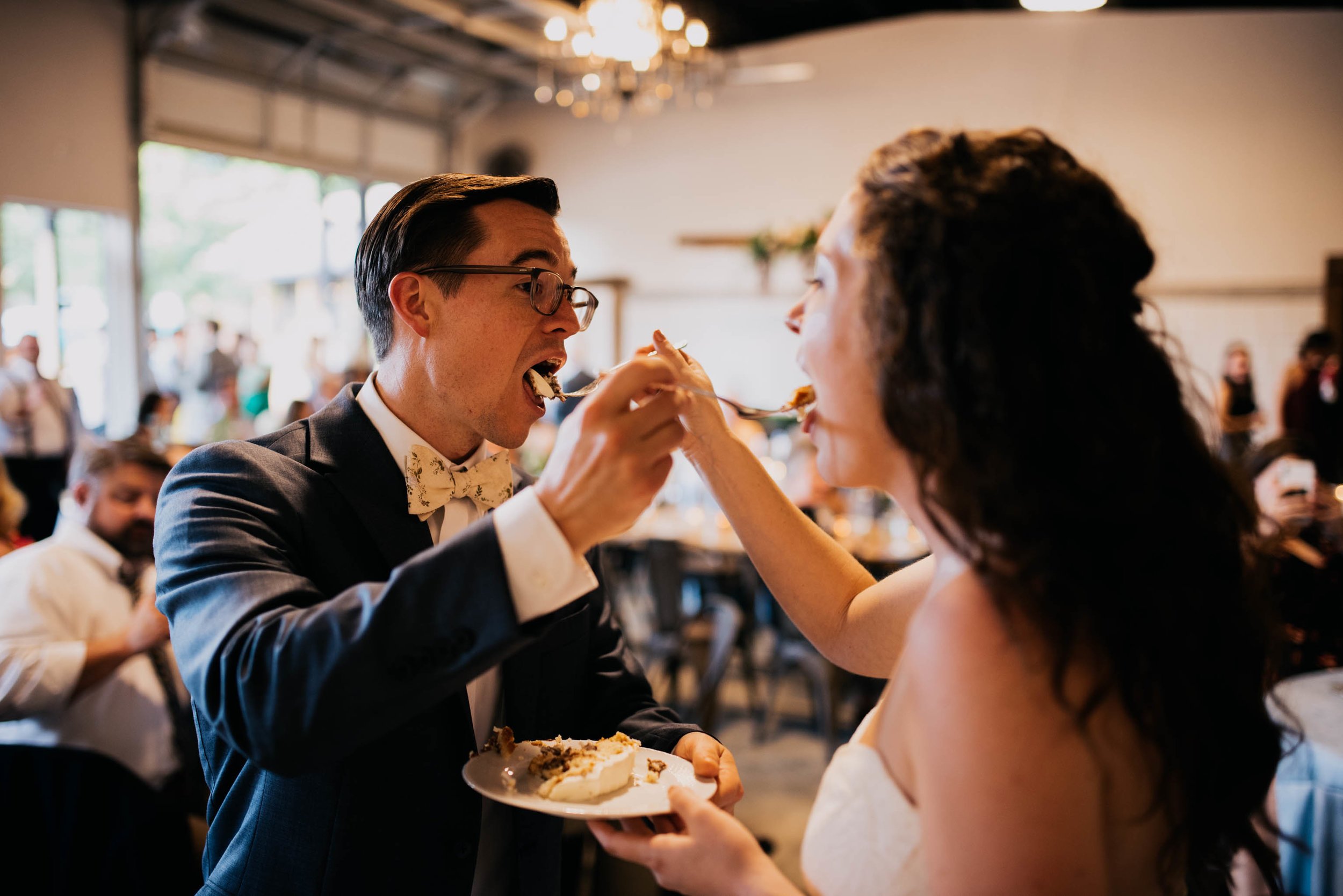 bride and groom feed each other wedding cake during their wedding ceremony