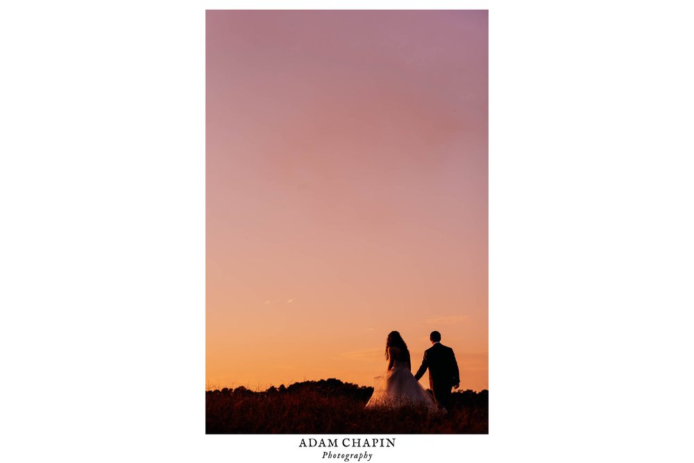 silhouette of bride and groom walking into the pink, peach and orange sunset