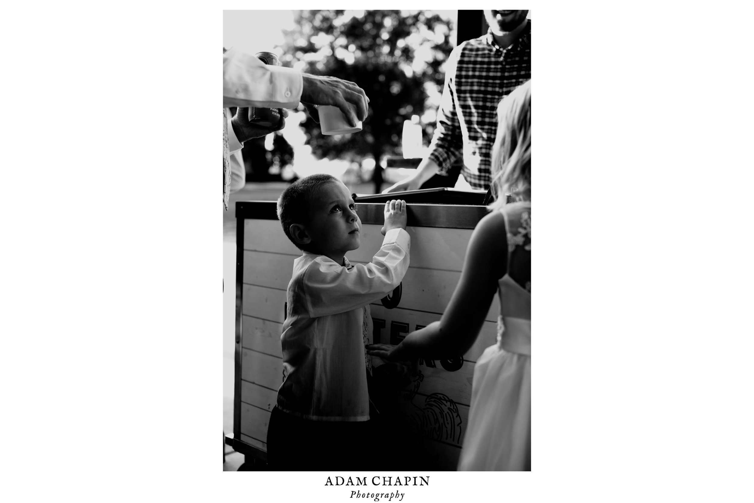 black and white photos of little kid trying to stand on tip toes to see ice cream options during wedding reception