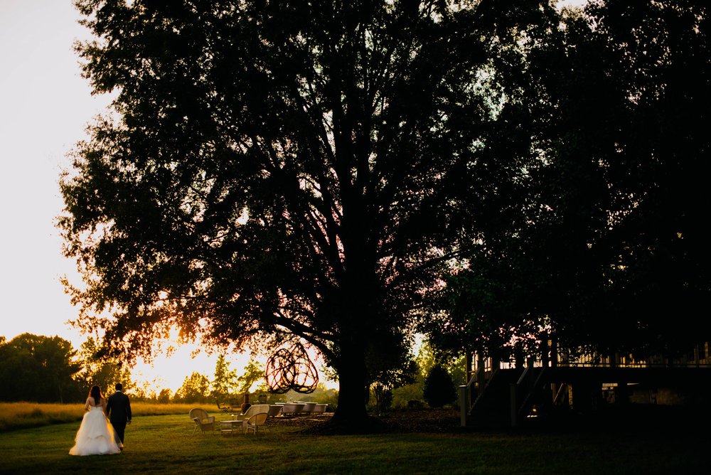 bride and groom walking under a huge oak tree during sunset