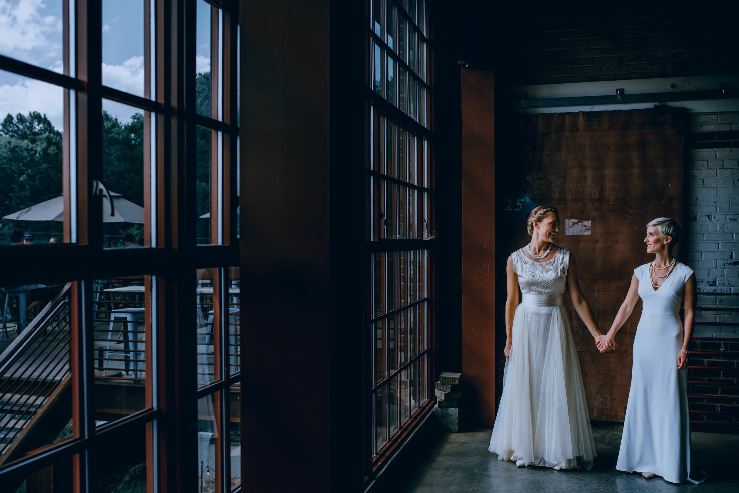 brides standing in the window light of the haw river ballroom
