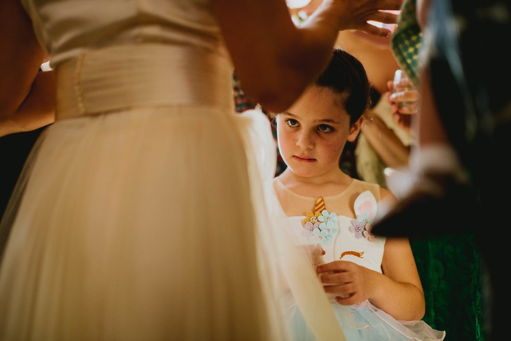 flower girl staring intently at the brides dress while the adults carry on conversation