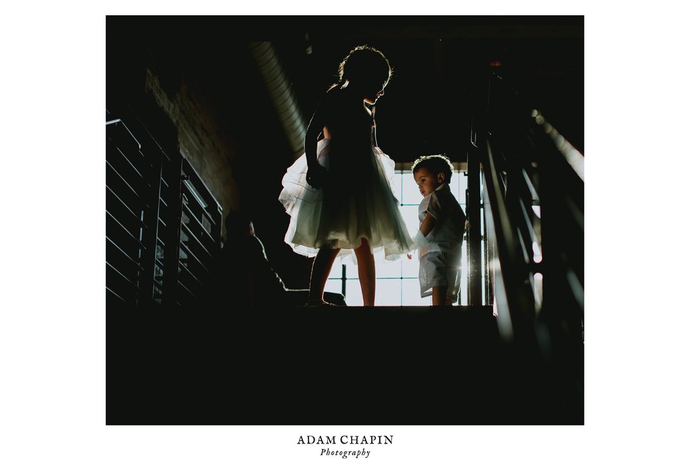 two children playing atop the stairs on the balcony of the haw river ballroom during the wedding reception