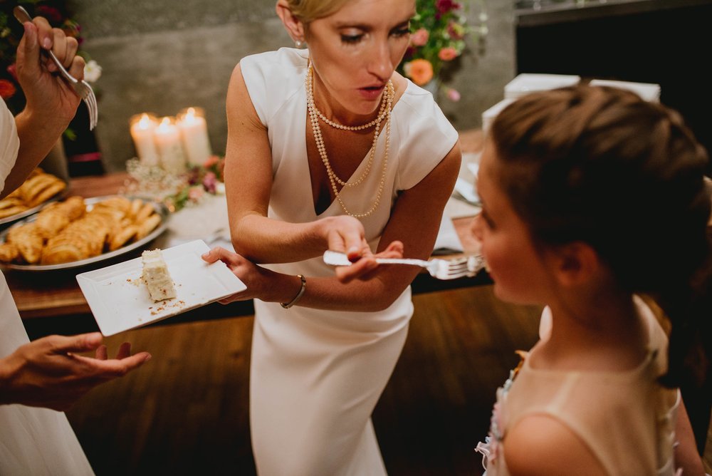 bride sharing some of the cake with the flower girl 