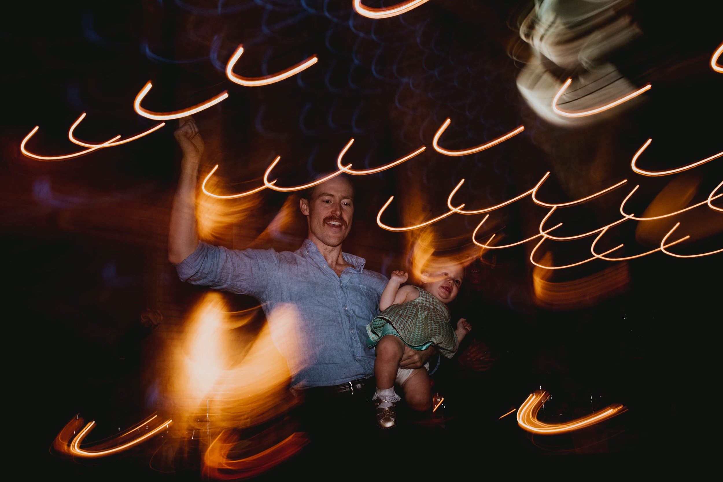 a wedding guest dancing with his infant during this haw river ballroom wedding reception