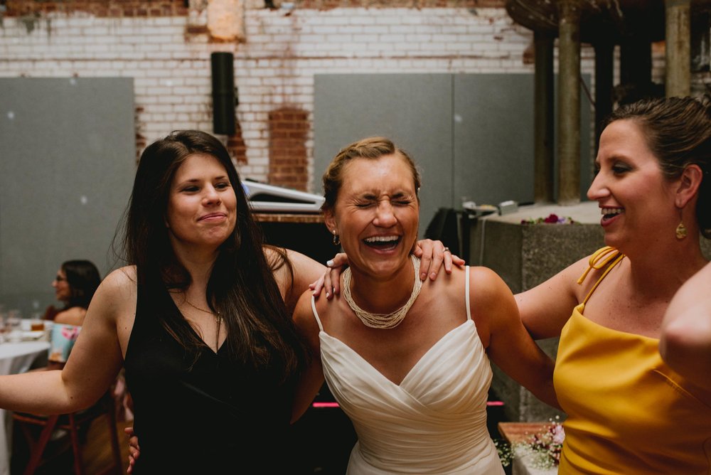 bride sharing a laugh with friends during haw river ballroom wedding