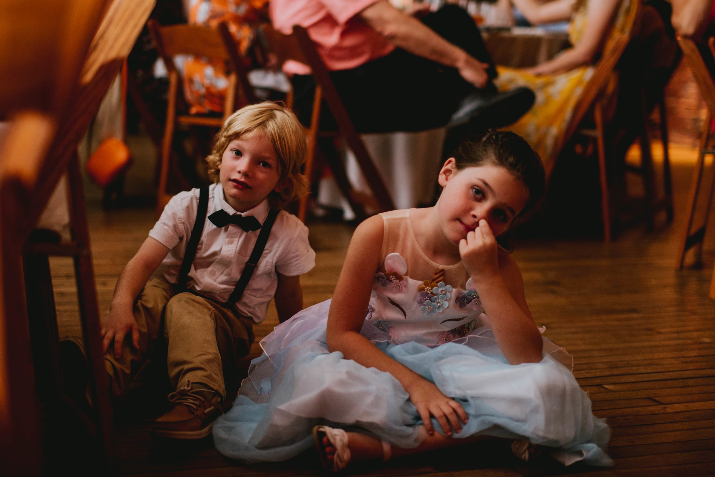 candid moment of kids sitting on the floor during toasts of this haw river ballroom wedding