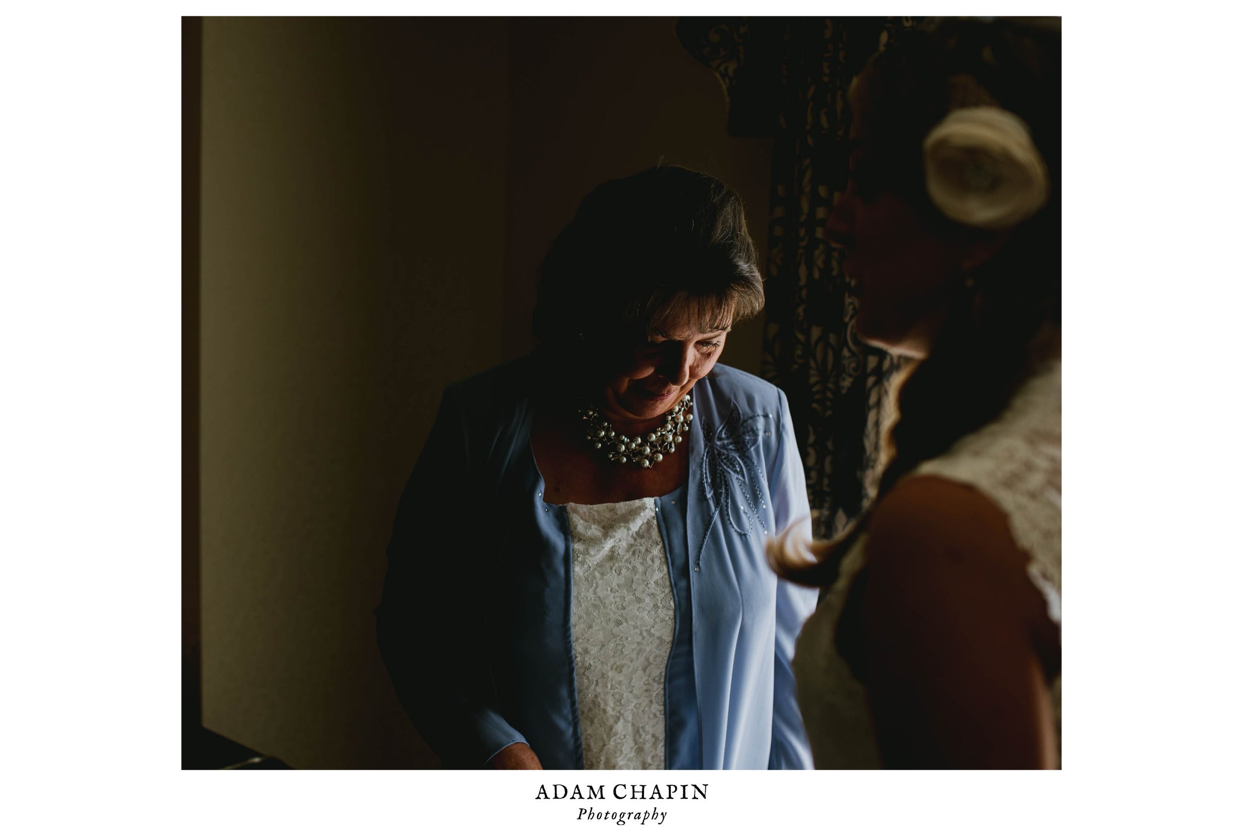 mother of bride looking at daughter in her dress