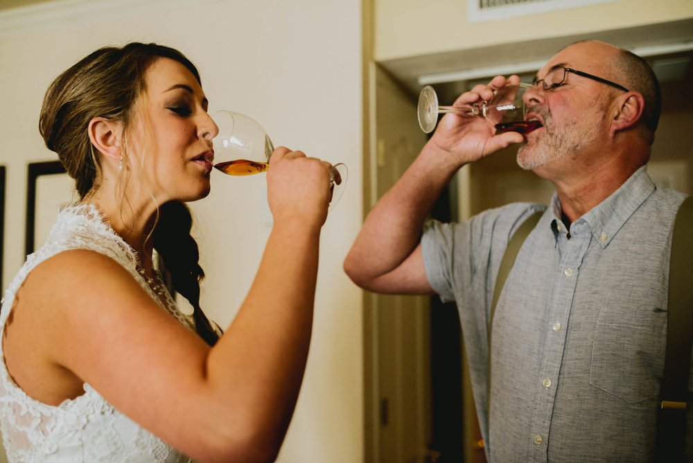 bride and father of the bride take a shot of whiskey