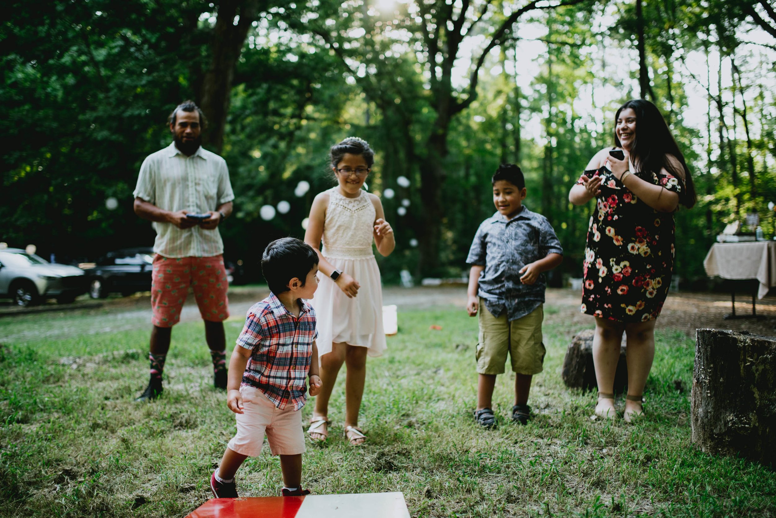 families playing cornhole during duke forest wedding reception