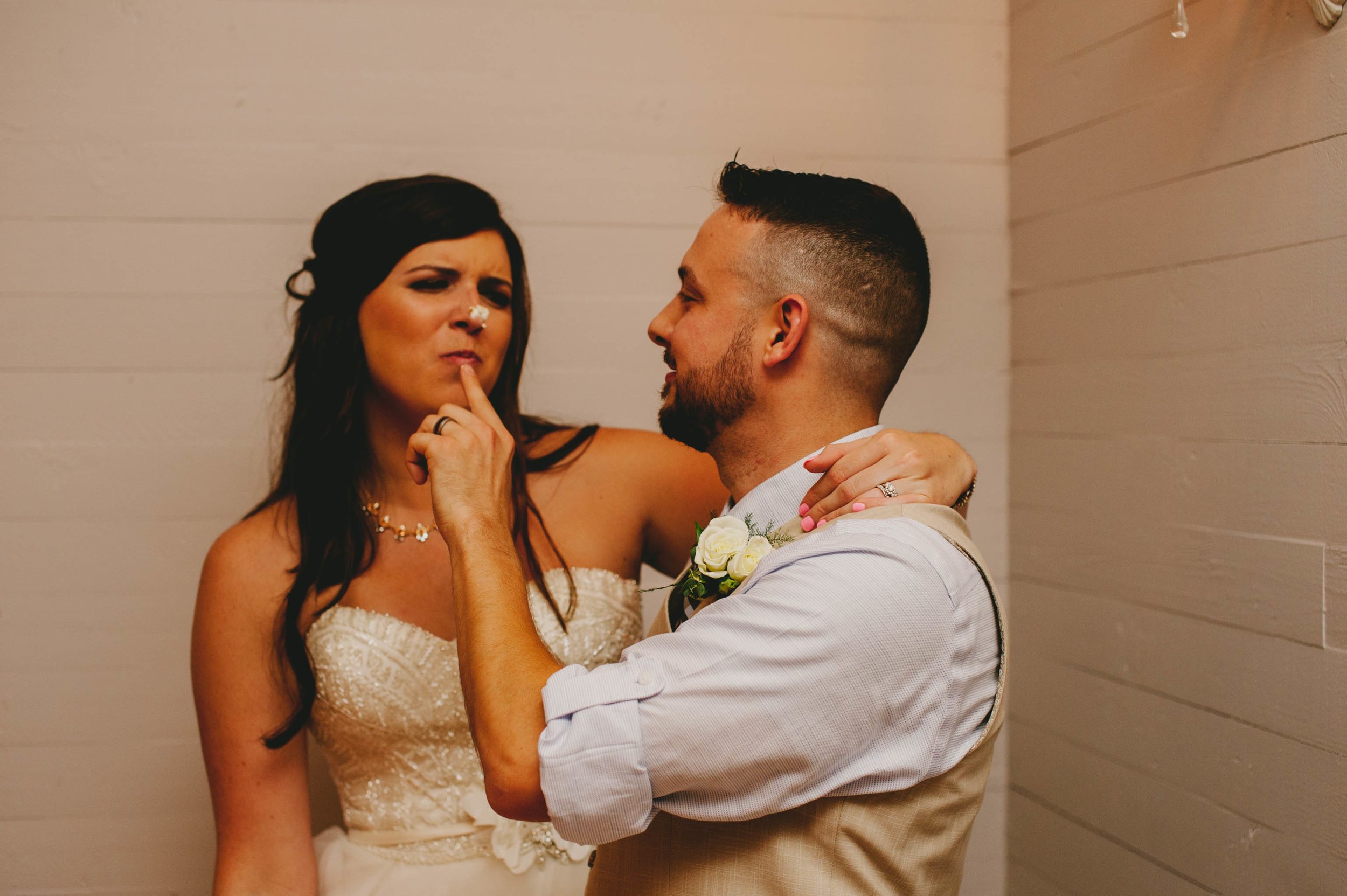 groom wipes cake frosting on brides nose