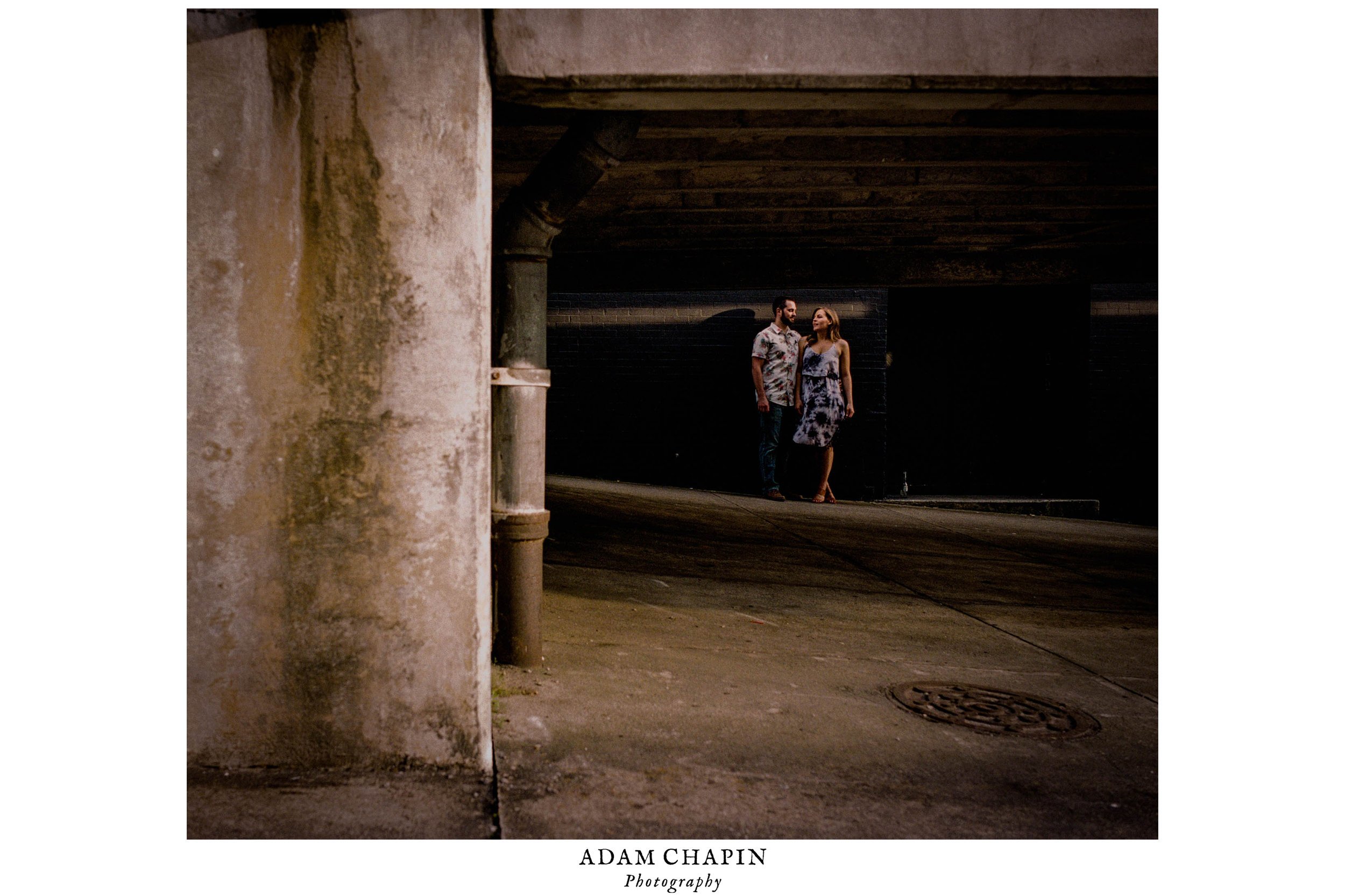 Couple talking under a bridge in some beautiful sunlight during their engagement photos in downtown Wilmington, North Carolina