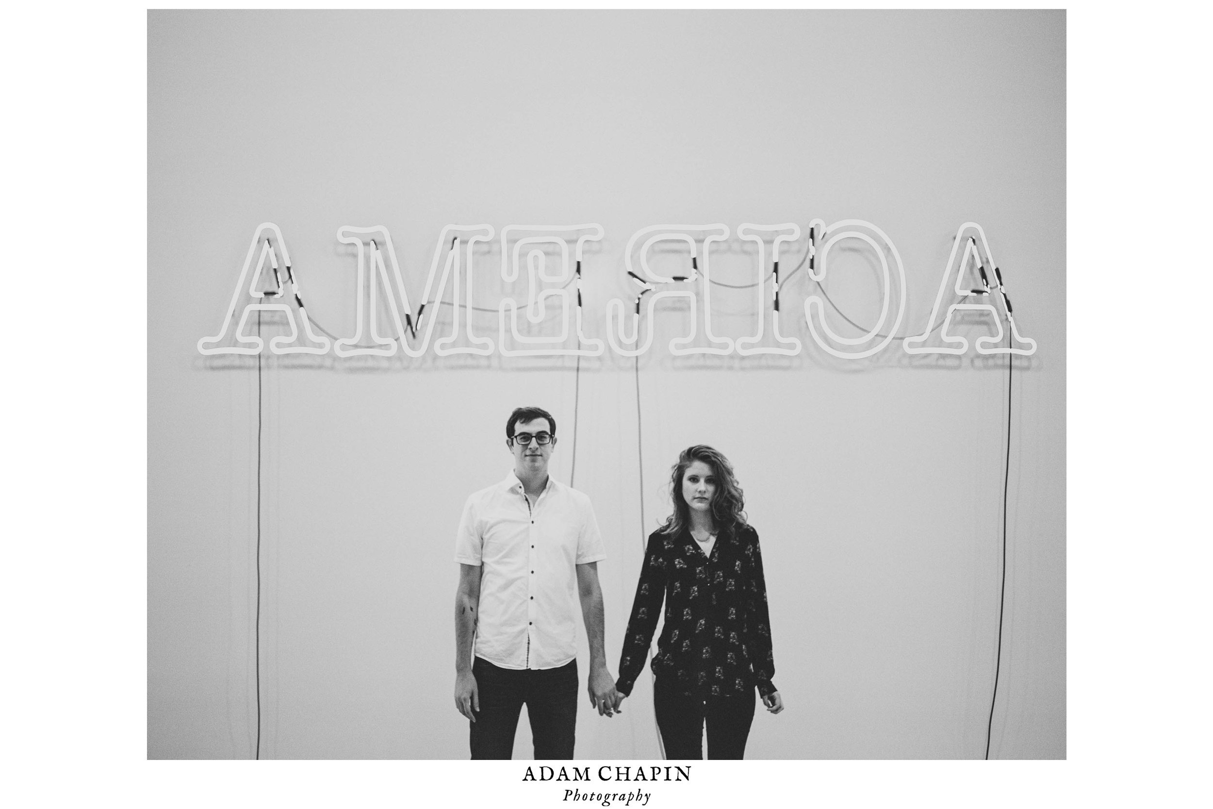 Couple holding hands in front of Glen Ligon's "America" neon piece at the Whitney Museum during their New York City engagement photos