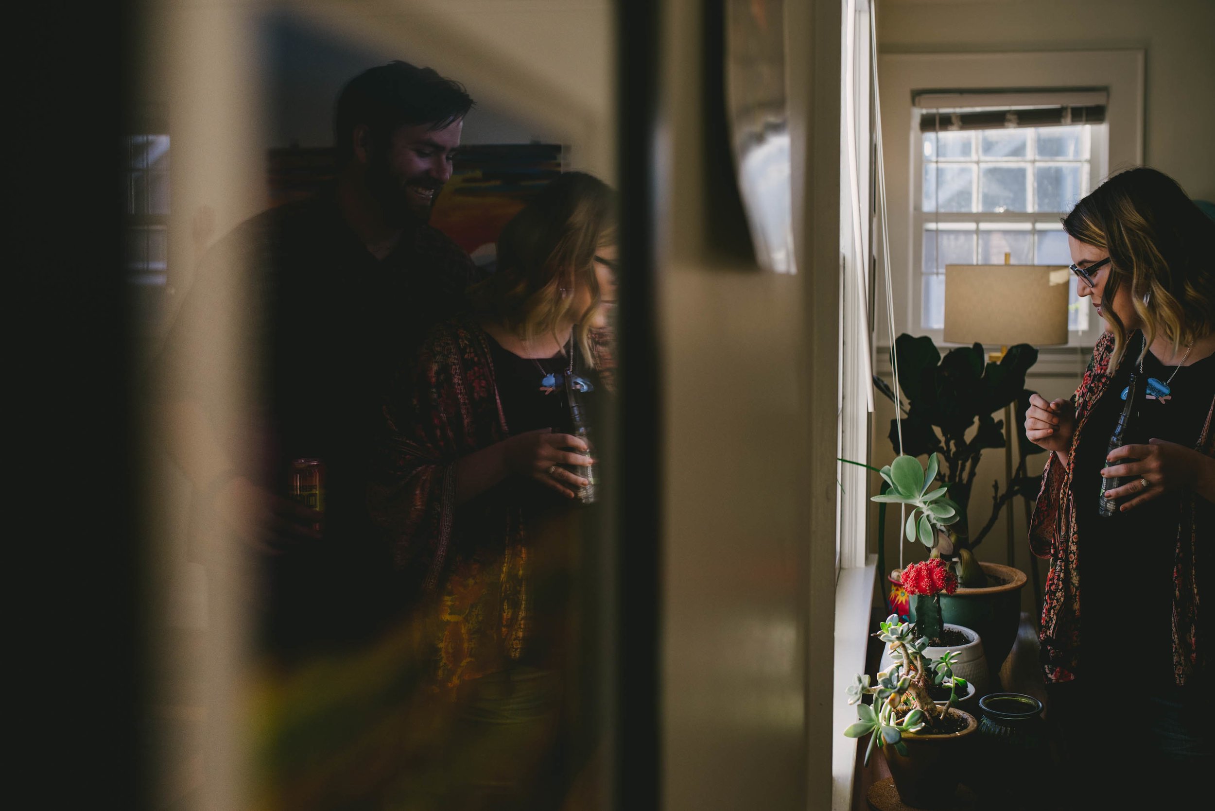 Couple drinking beers and admiring their plants at home during their engagement photos in Greensboro, North Carolina