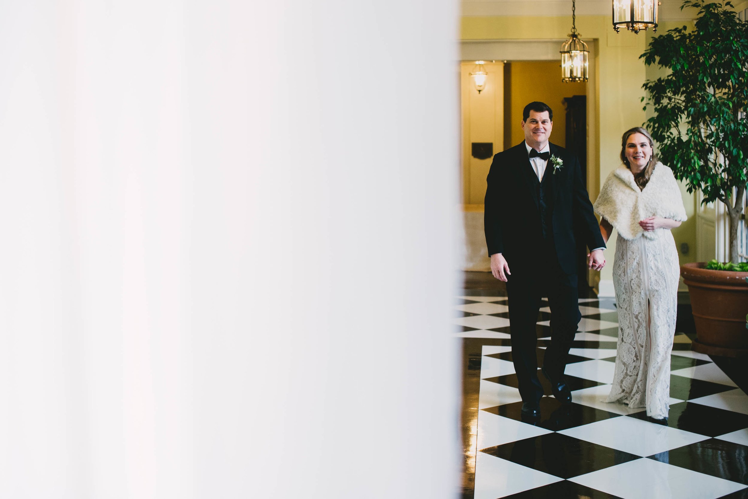 the bride and groom walking down the classic black and white tiles Carolina Inn hallway