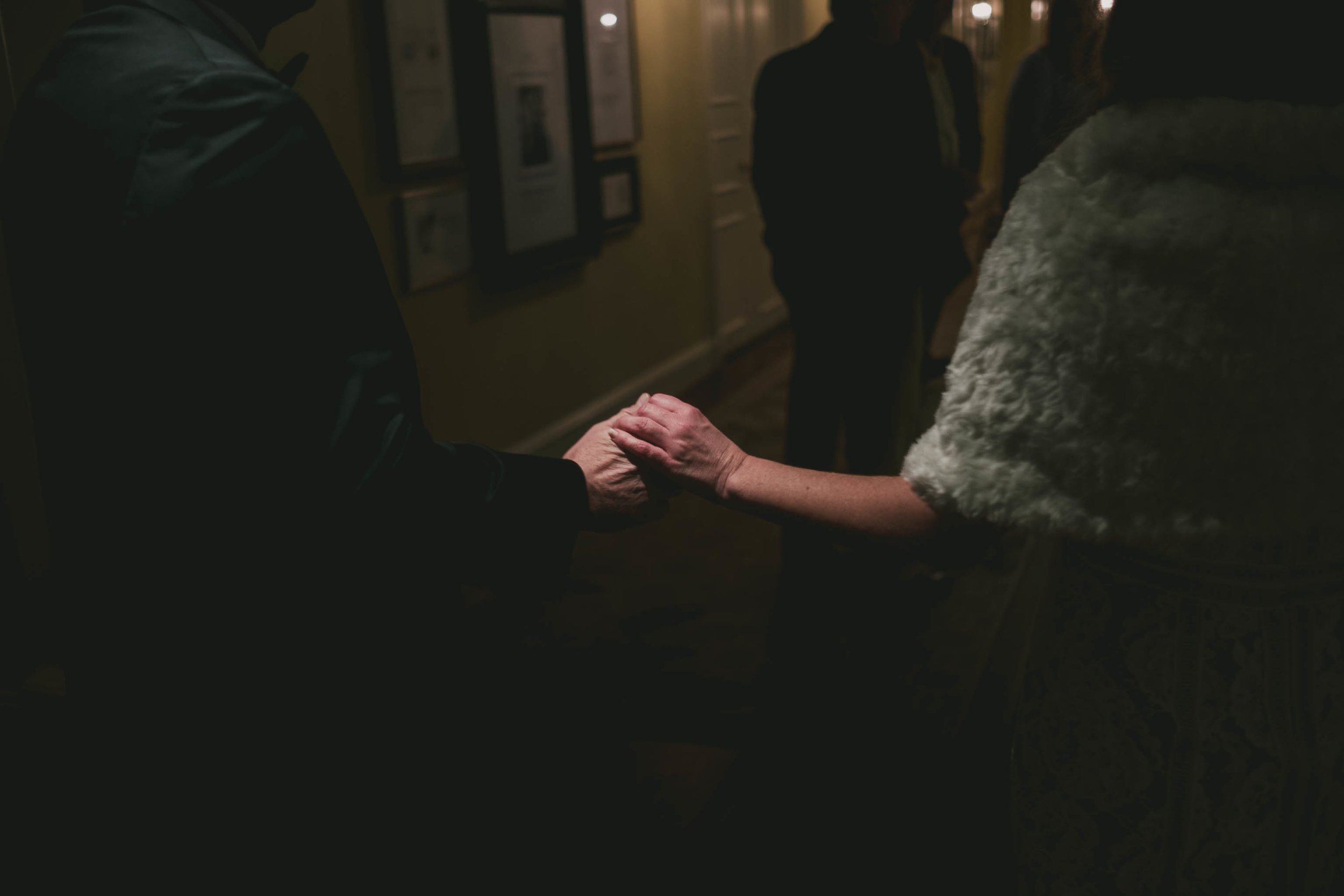 the bride and groom holding hands in a dimly lit hallway of the Carolina Inn