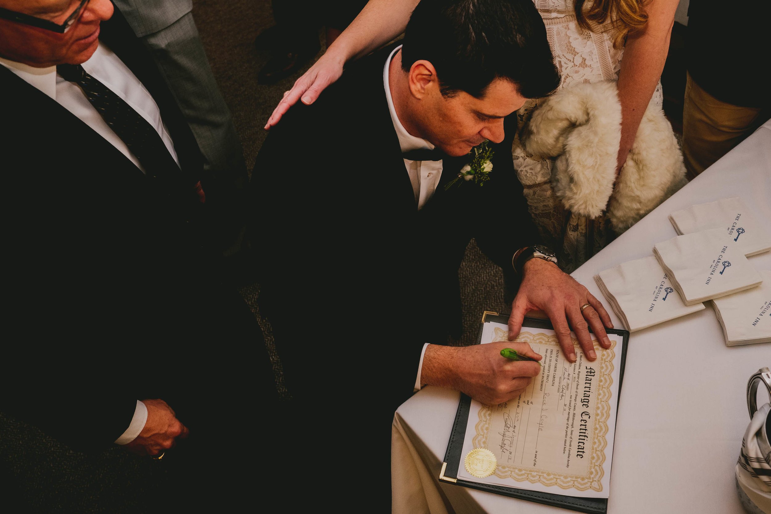 the bride and groom signing their marriage license