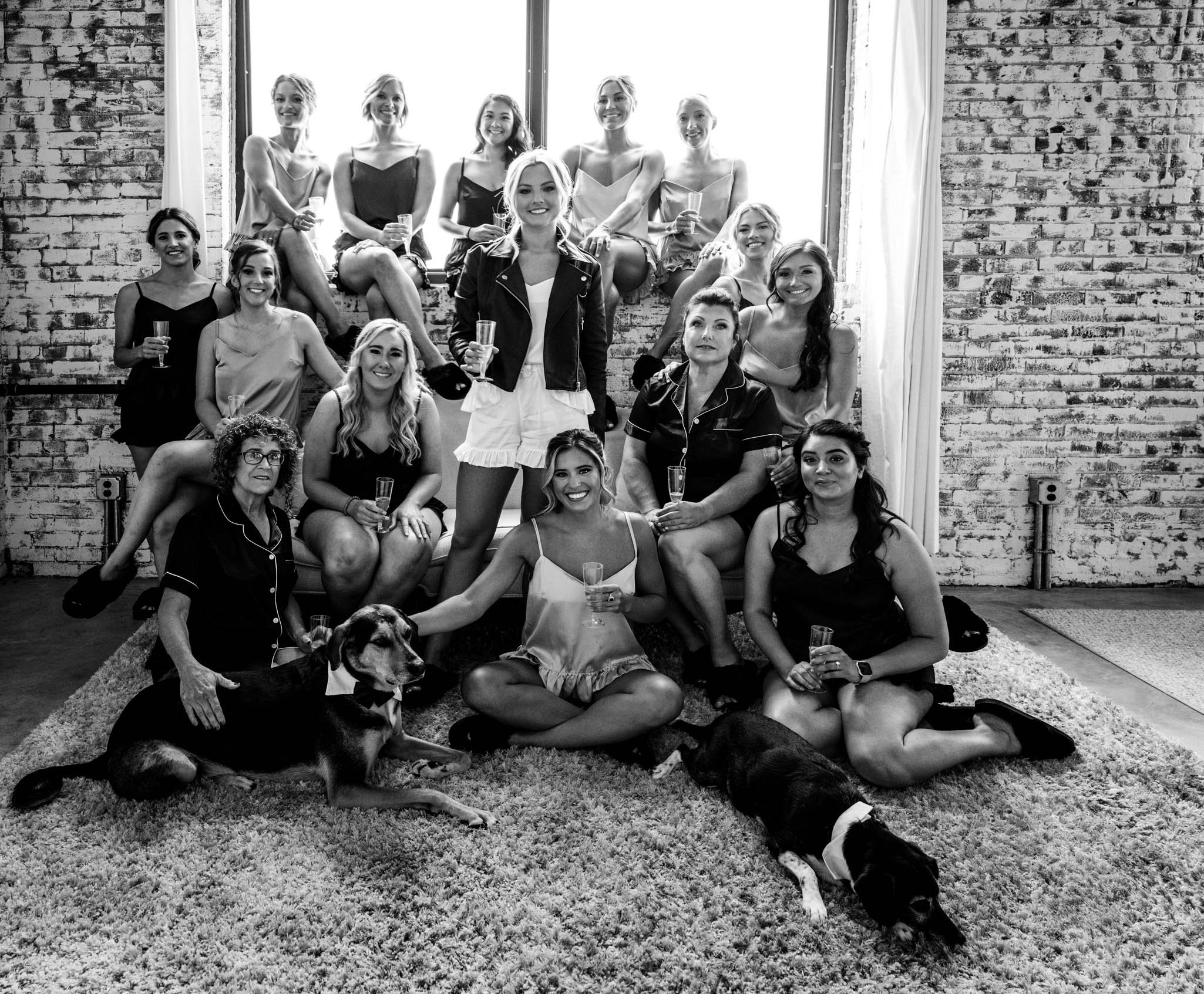 bride and her bridesmaids pose together with dogs and champagne before the wedding