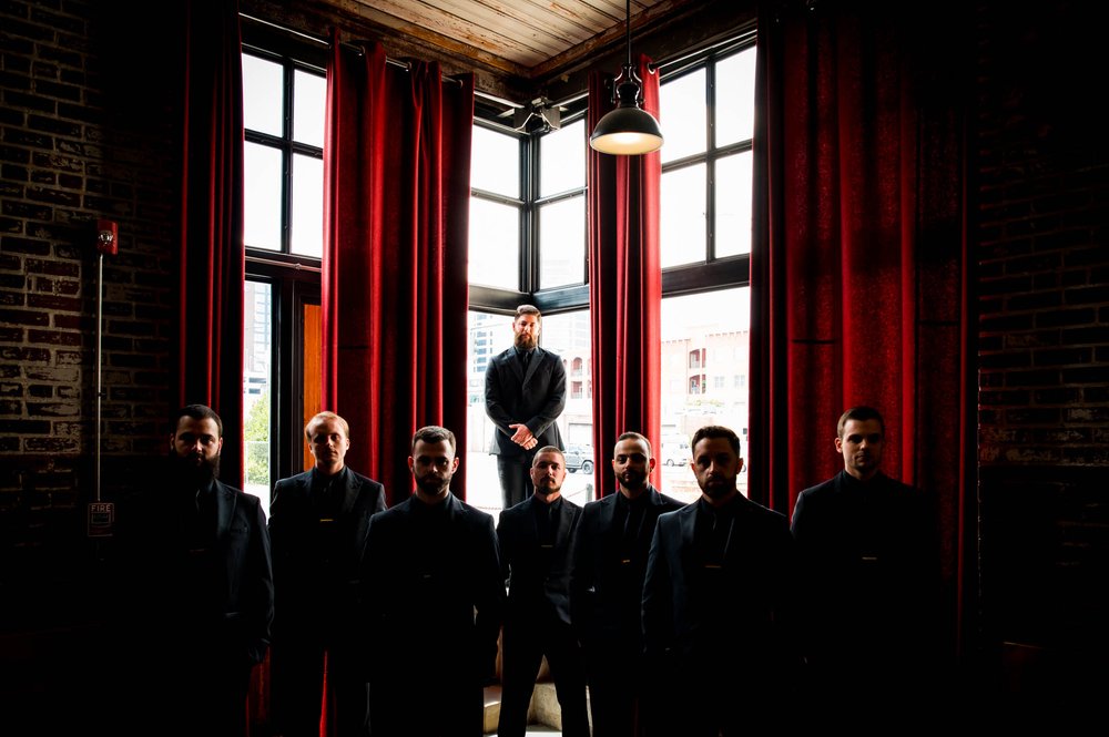 groom and groomsmen pose in dramatic light