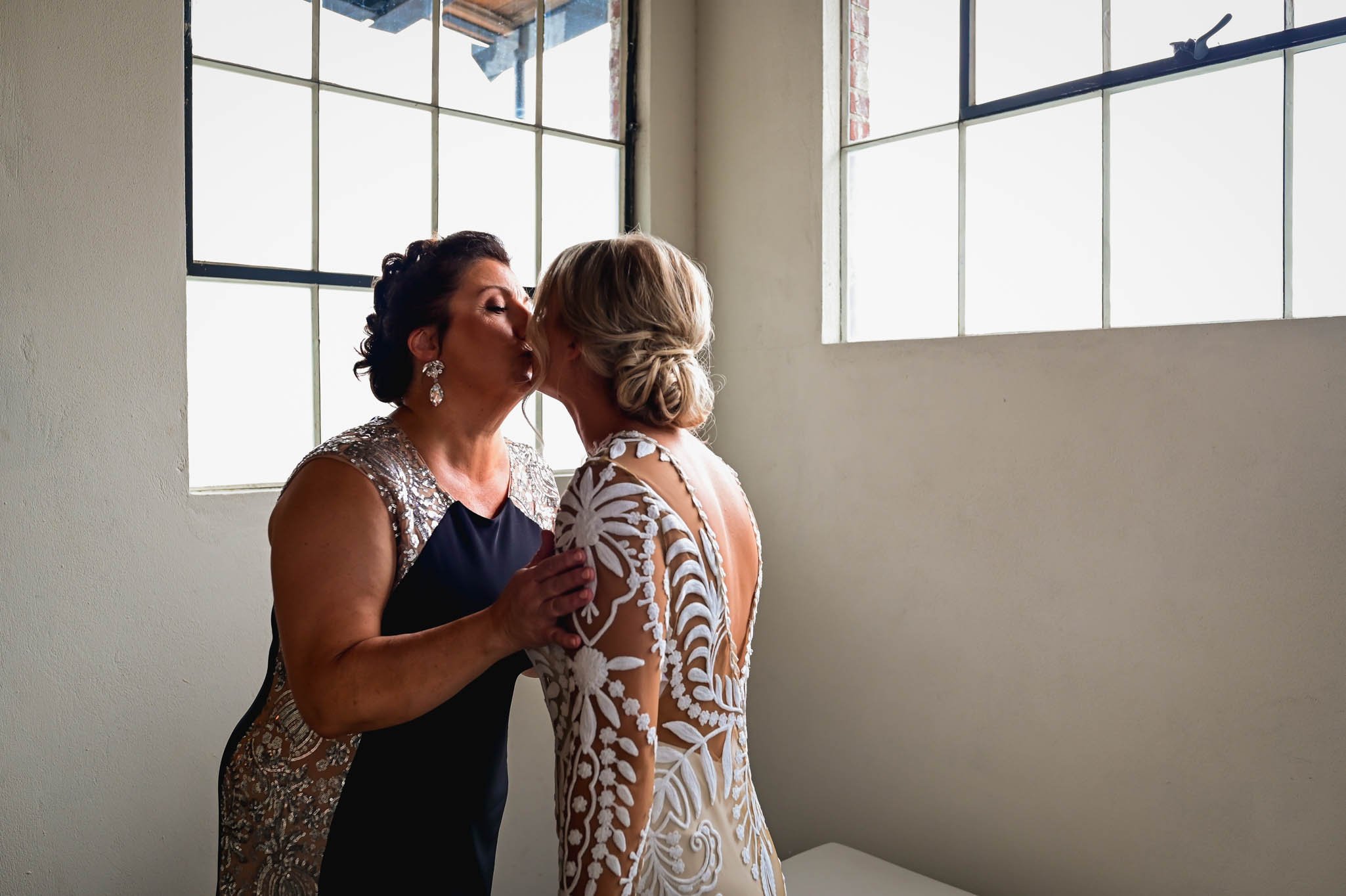mother of the bride and the bride share a quick kiss before the dress reveal