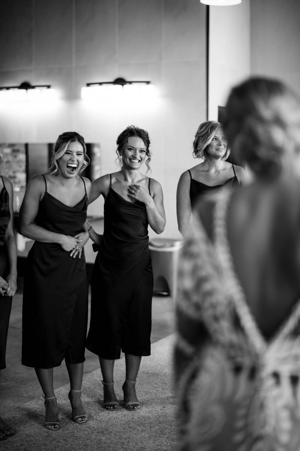 bridesmaids smile and cry as they see the bride in her dress