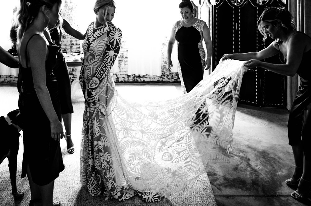 bride looks back as bridesmaid fluff her wedding dress train