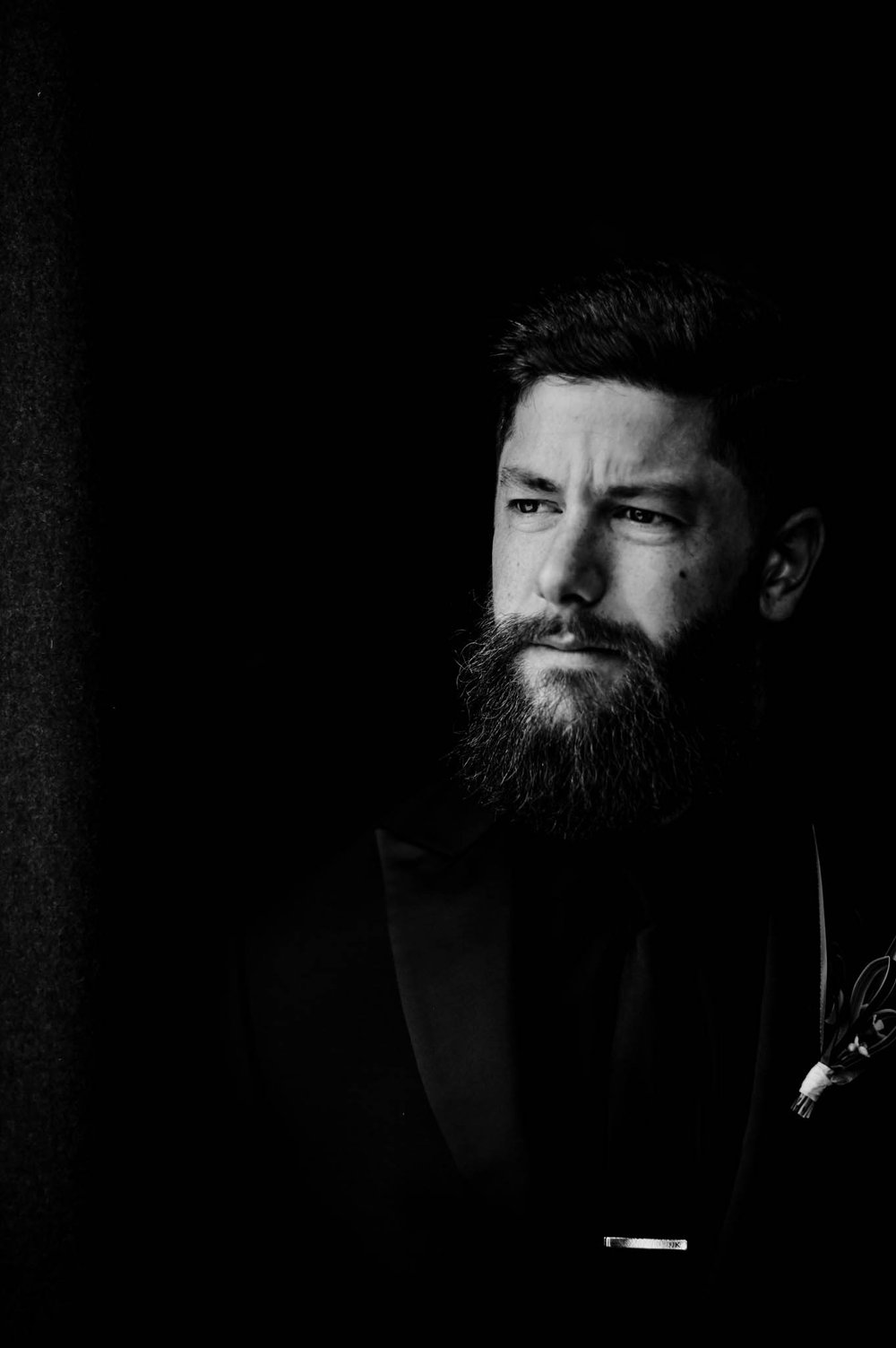 groom poses in dark dramatic light before the wedding