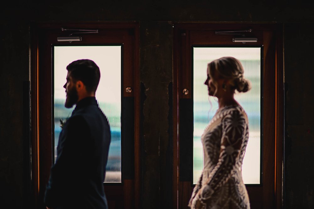 bride and groom stand in the frames of the door frame just before their first look