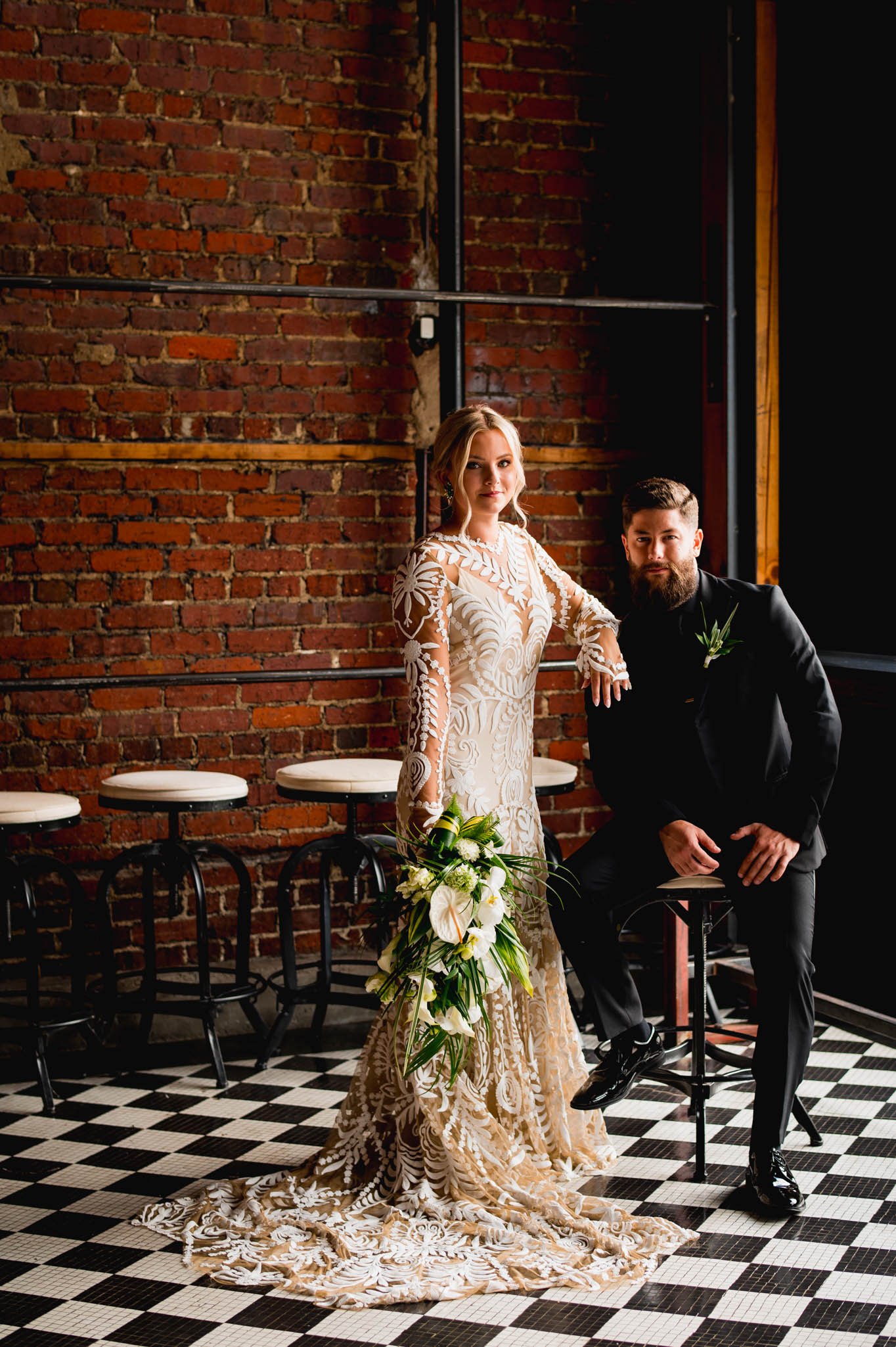 bride and groom pose on checkered floor by the front window