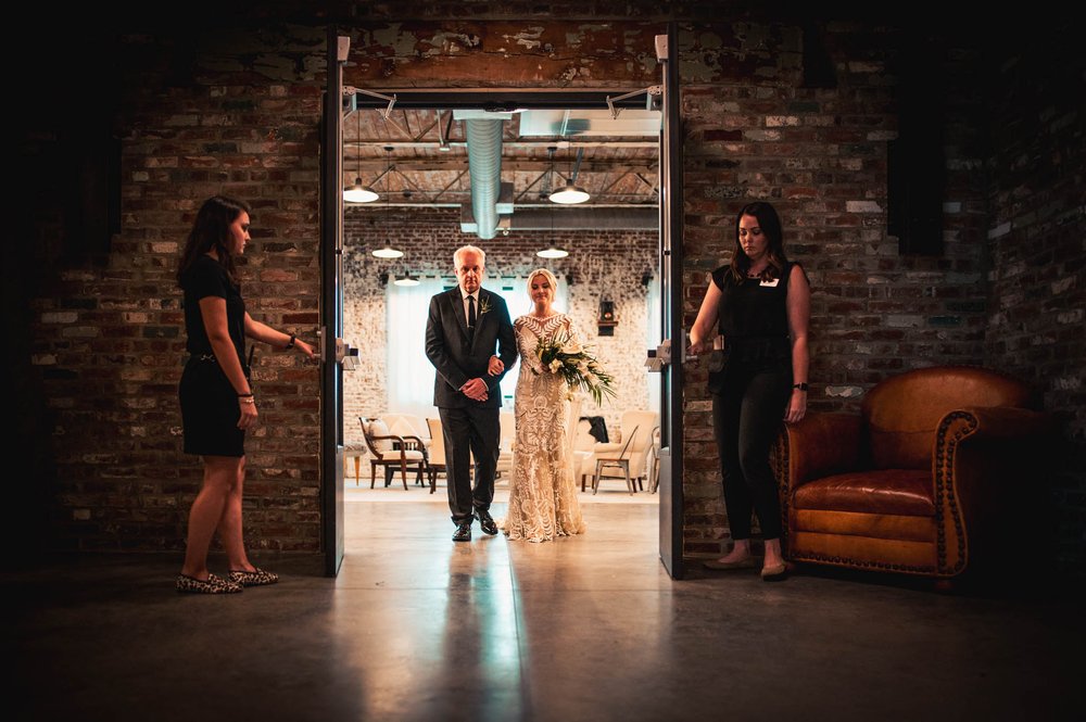 father of the bride and the bride step into the ceremony